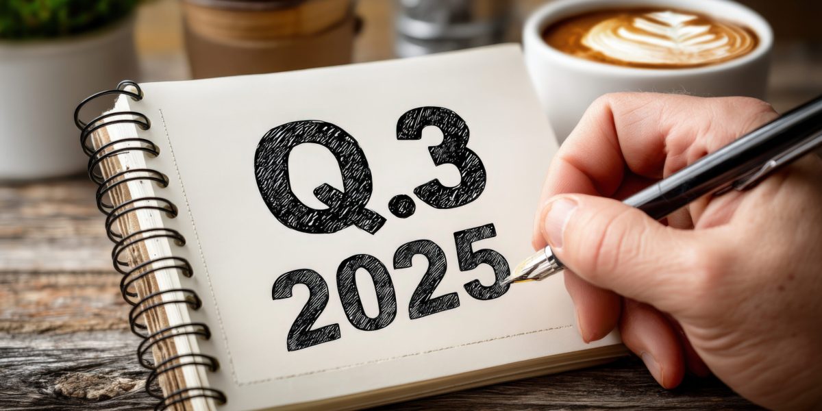 A hand writes "Q3 2025" in a notebook, symbolizing strategic planning. The warm coffee cup and rustic table create an inviting workspace atmosphere.